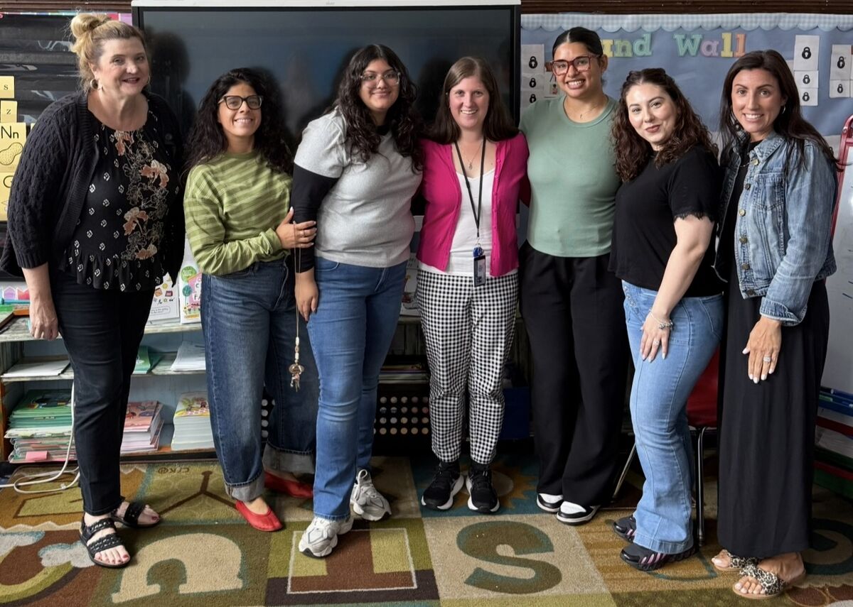 The 1st Grade teaching team standing together in front of a classroom library.