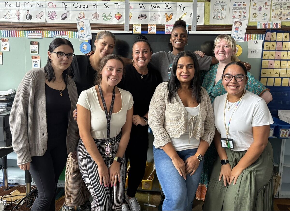 The 2nd Grade teaching team gathered in front of a classroom alphabet display.