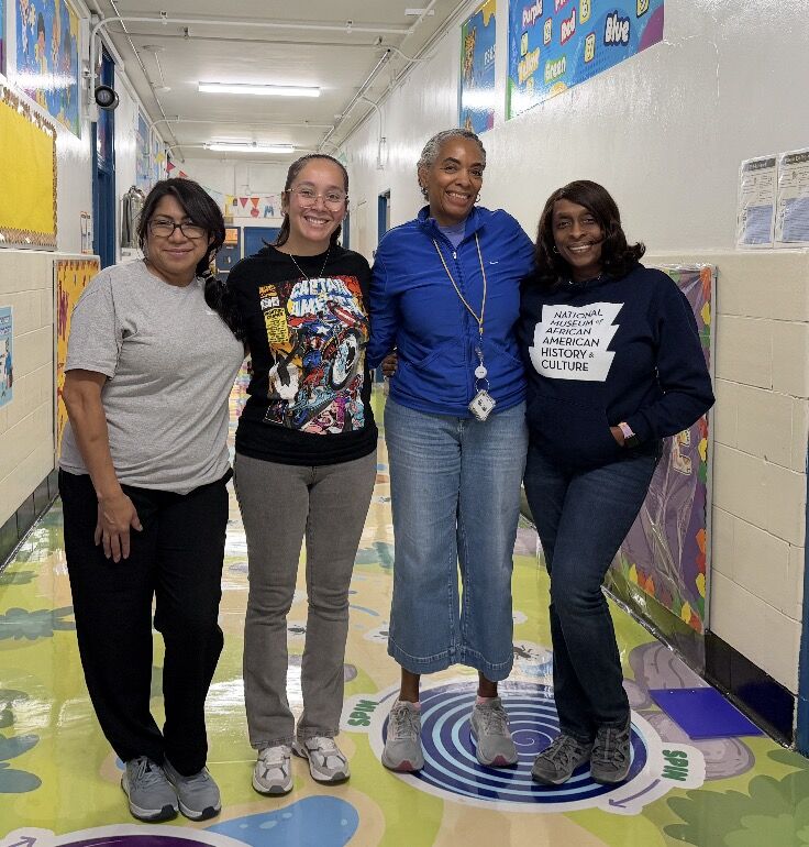 The Pre-Kindergarten teaching team standing together in a colorful PS 85 hallway.