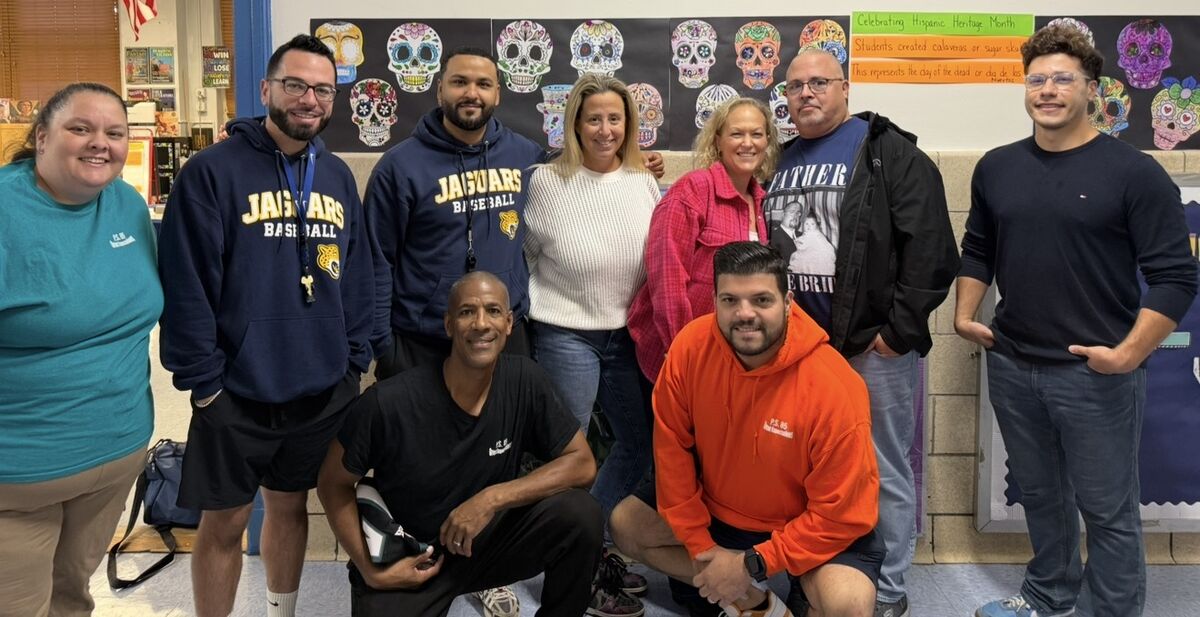 Members of the Enrichment team gathered in front of a Hispanic Heritage Month bulletin board.